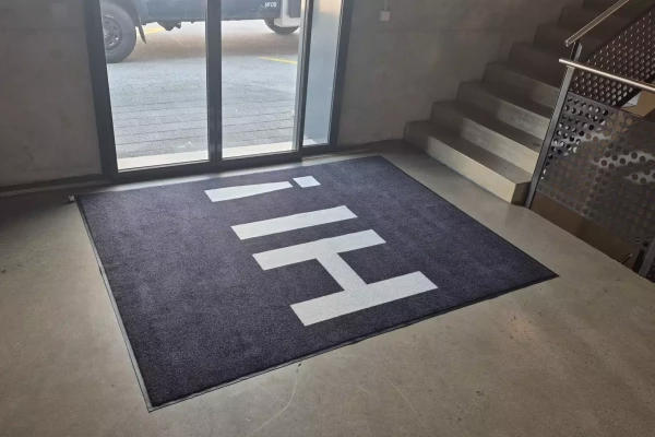 Tapis de sol noir sur mesure avec un texte sur mesure dans un halle d'entrée