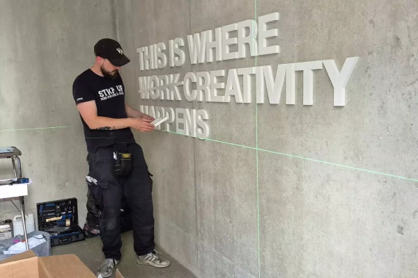 photo d'un homme qui colle des lettres 3d contre un mur